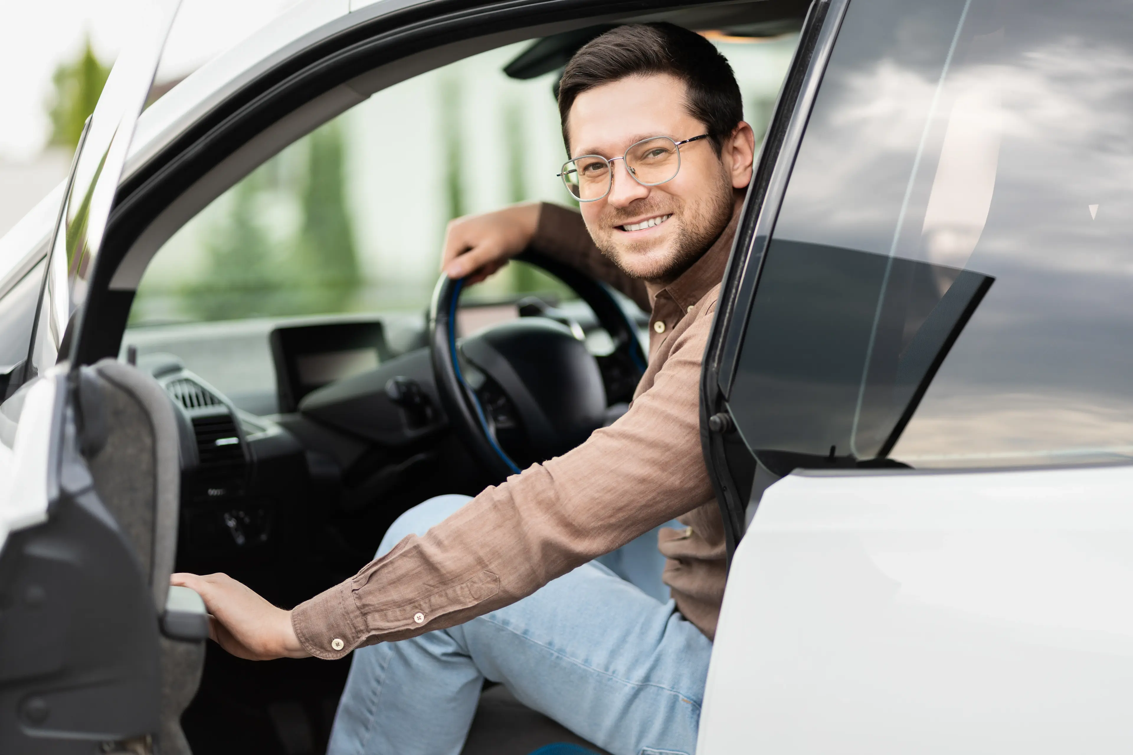 Homem sorridente dirigindo carro assinado